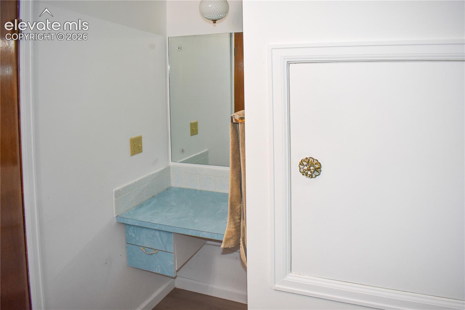 Vanity area featuring a wall-mounted mirror, built-in countertop, and integrated drawer storage