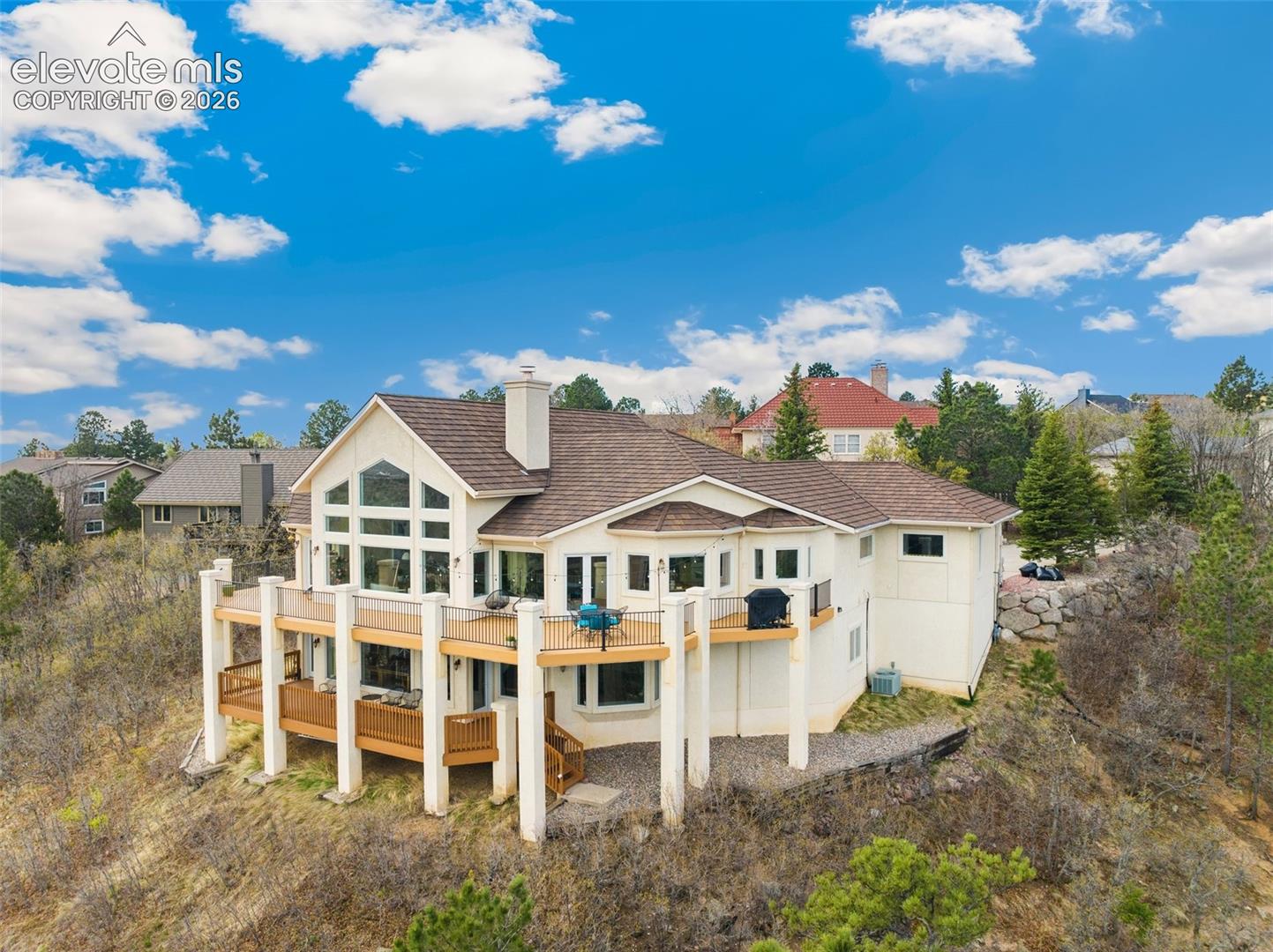 Hillside residence featuring a multi-level deck, expansive window arrangements, and a prominent chimney