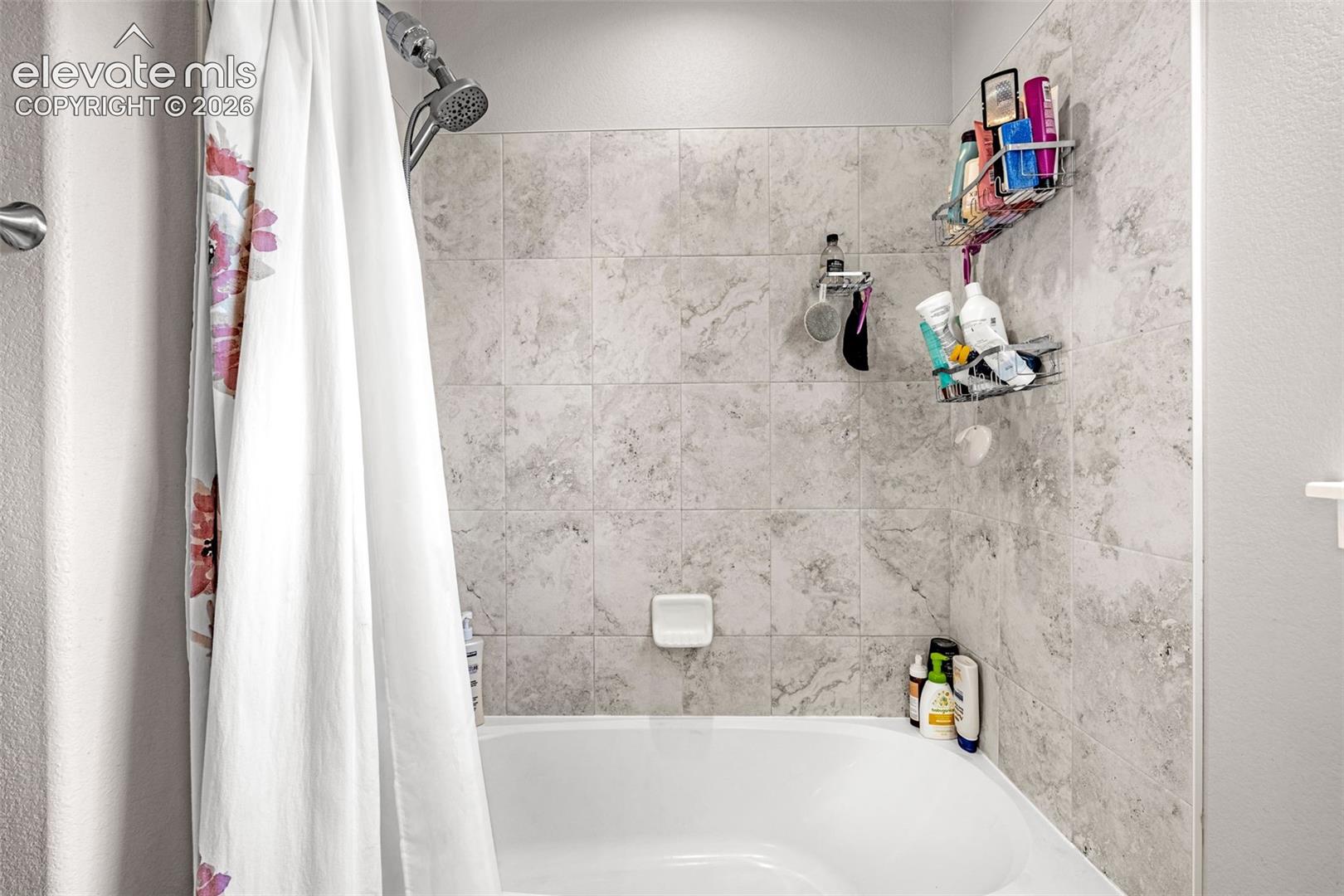 Bathtub and shower combination featuring neutral-toned tile surround