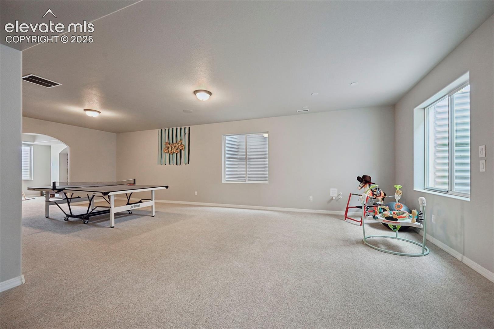 Spacious room featuring neutral carpeting, recessed ceiling lighting, and multiple egress windows
