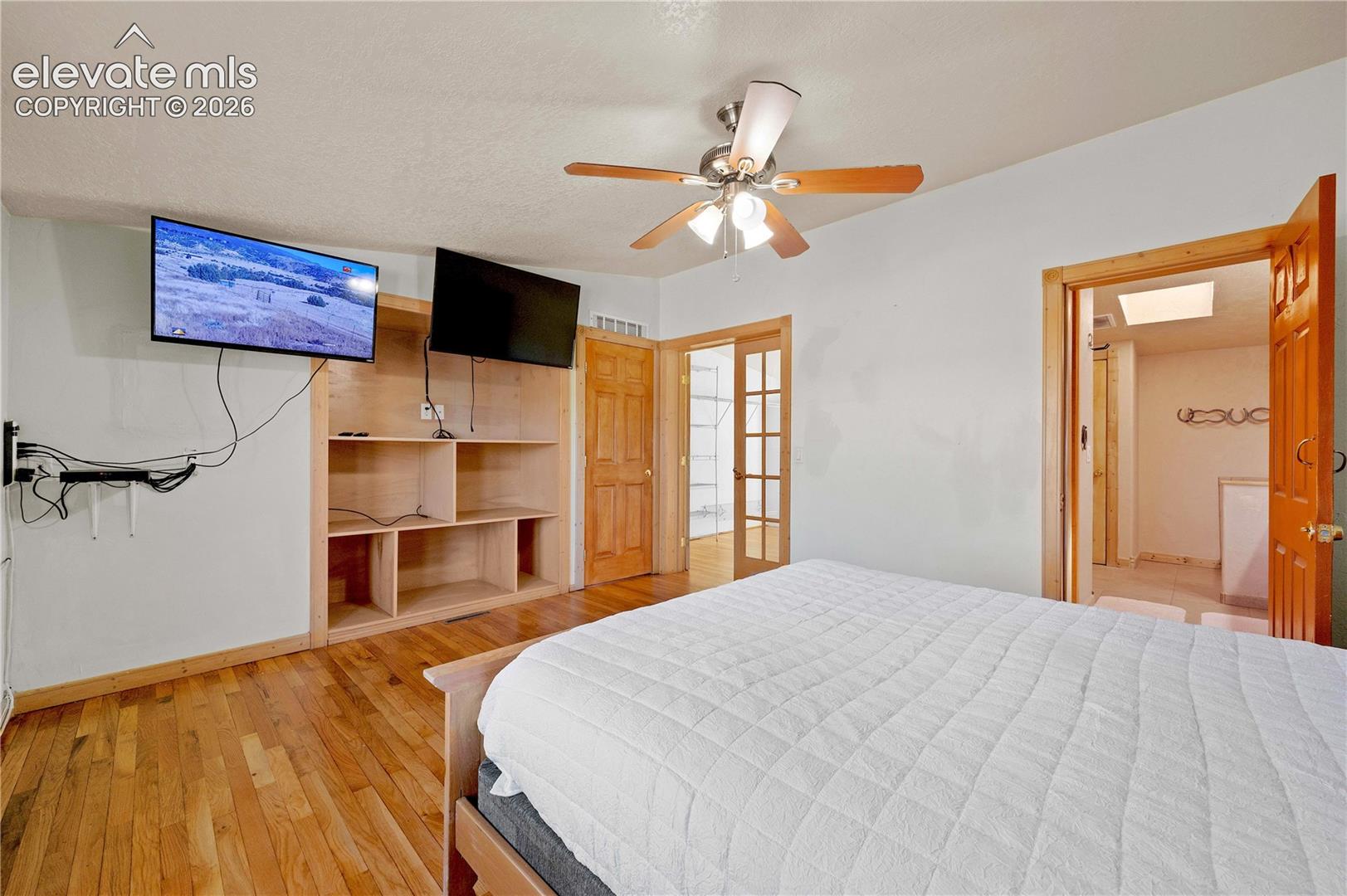 Bedroom featuring a textured ceiling, hardwood / wood-style flooring, a skylight, and ceiling fan