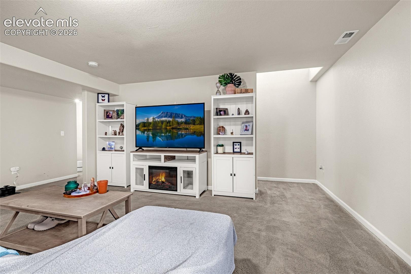 Spacious room featuring carpeting, recessed lighting, and a built-in media console with an electric fireplace