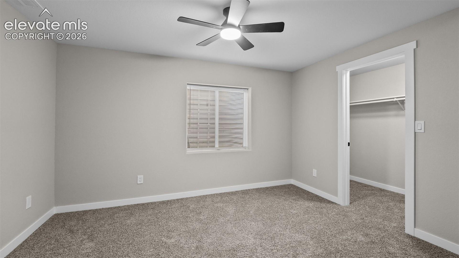 Gray carpeting, white trim, recessed window with blinds, and ceiling fan with lighting