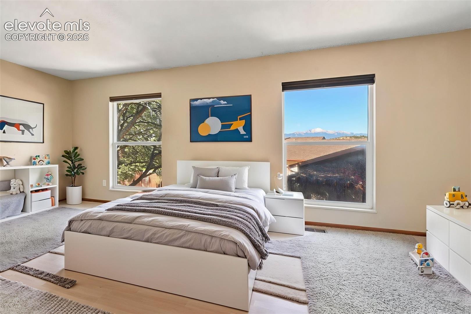 Spacious room featuring neutral wall tones, wall-to-wall carpeting, and large dual-pane windows offering mountain scenery