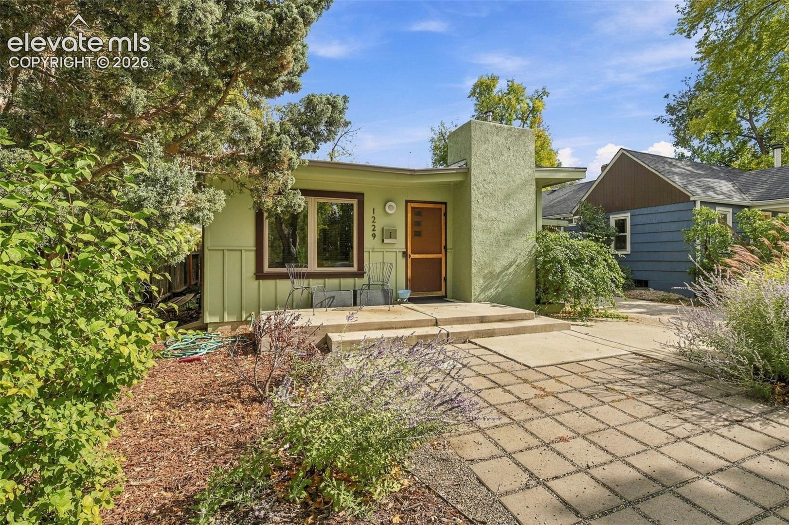 Stucco exterior featuring vertical paneling, a concrete front patio, and square-paver hardscaping