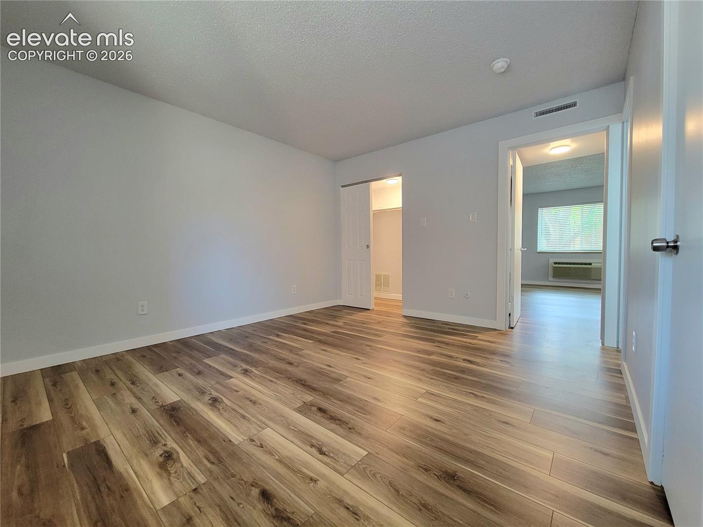 Primary Bedroom featuring wood-finish flooring, and his & hers closet