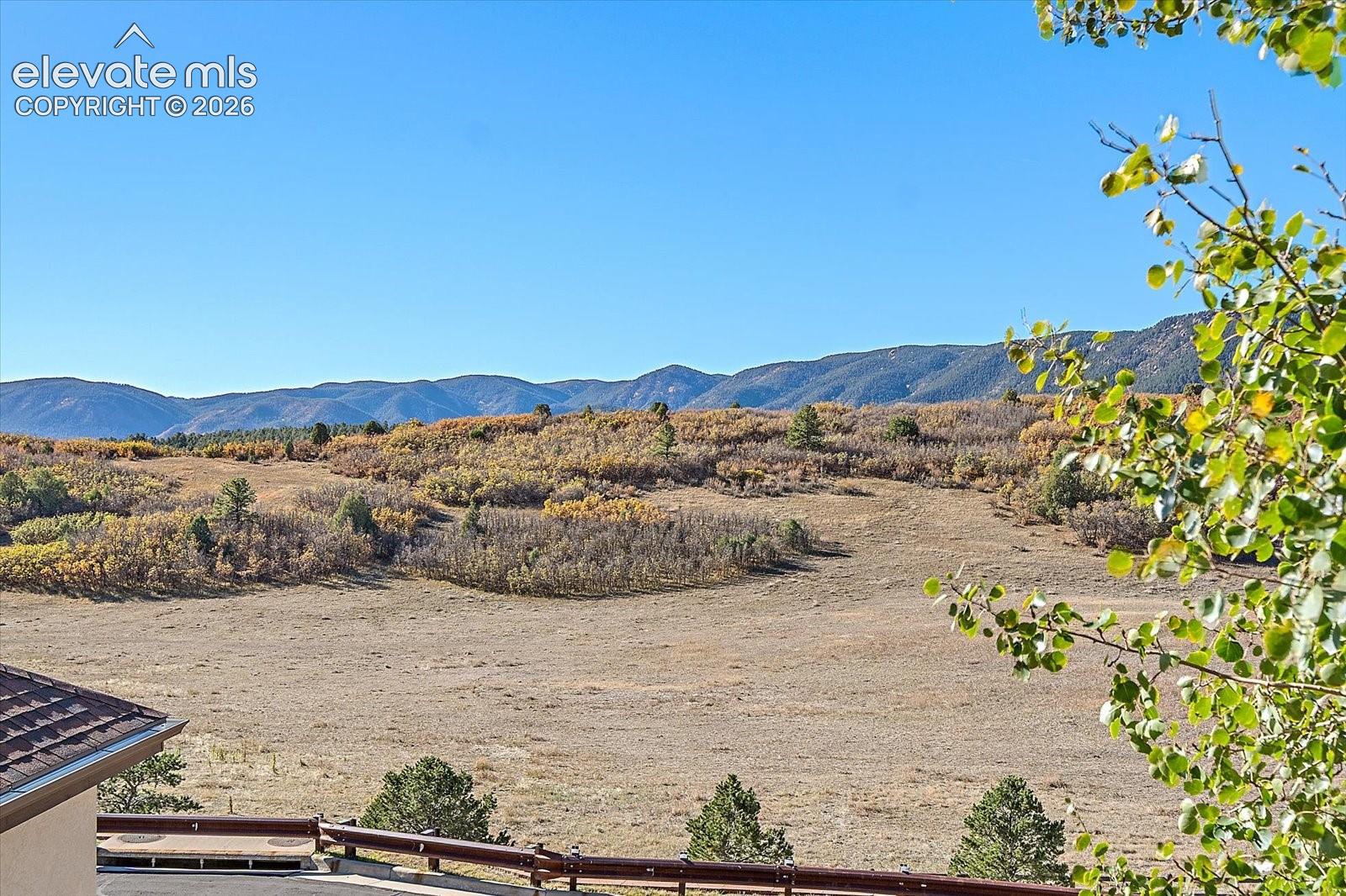 Expansive terrain featuring mature trees, native vegetation, and a prominent mountain range backdrop