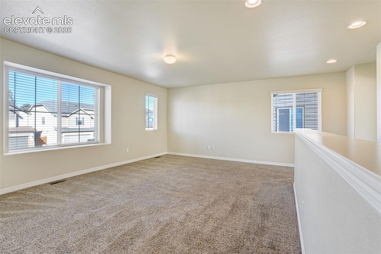 Carpeted room with recessed lighting, a large picture window, and a secondary window