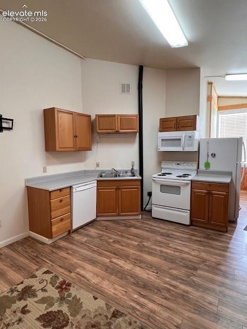 Kitchen featuring wood cabinetry, laminate countertops, integrated white appliances, and wood-finish flooring