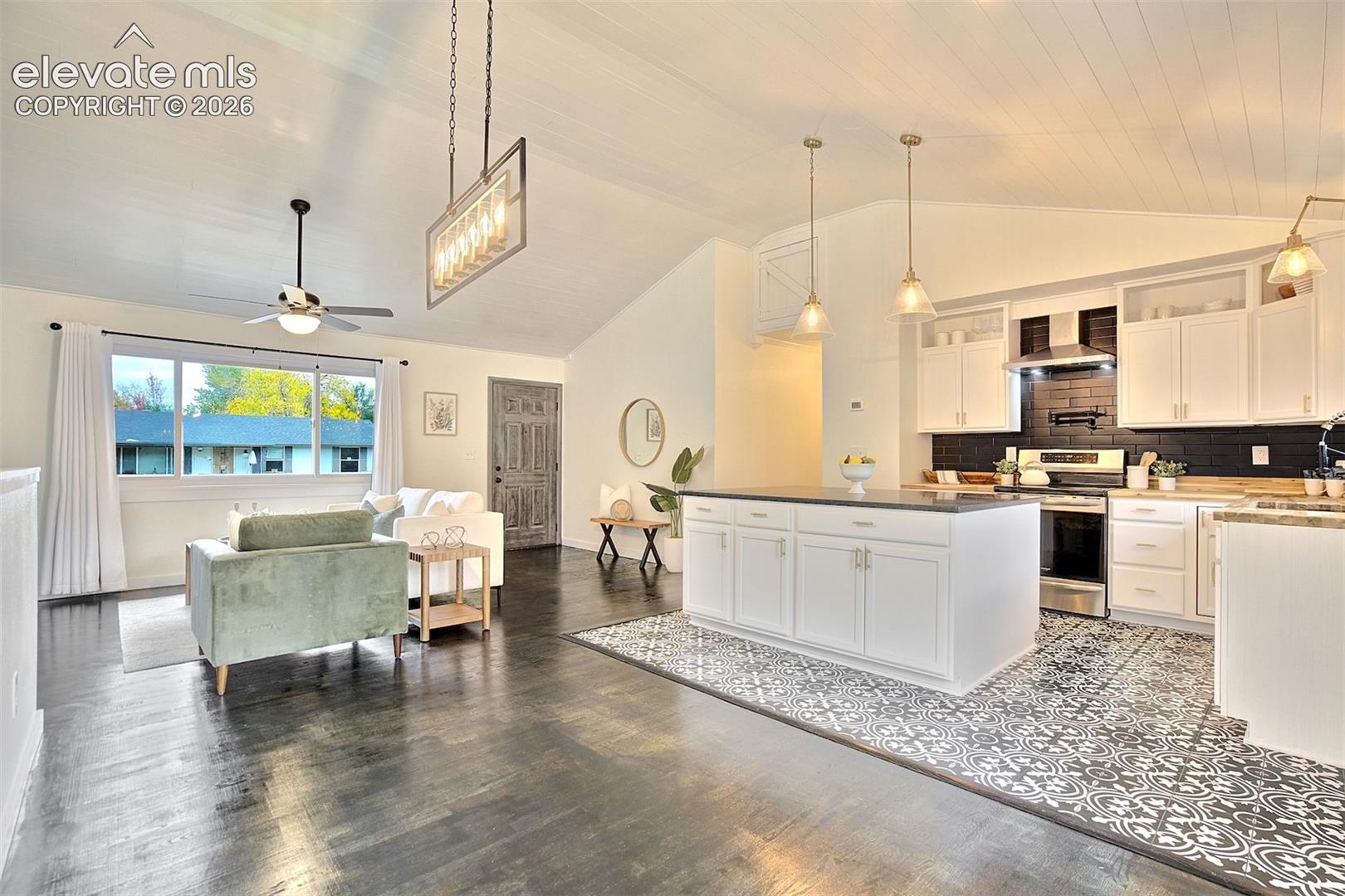 Vaulted ceilings, kitchen island with stone-finish countertop, patterned tile flooring, dark-toned wood-finish flooring, and subway tile backsplash