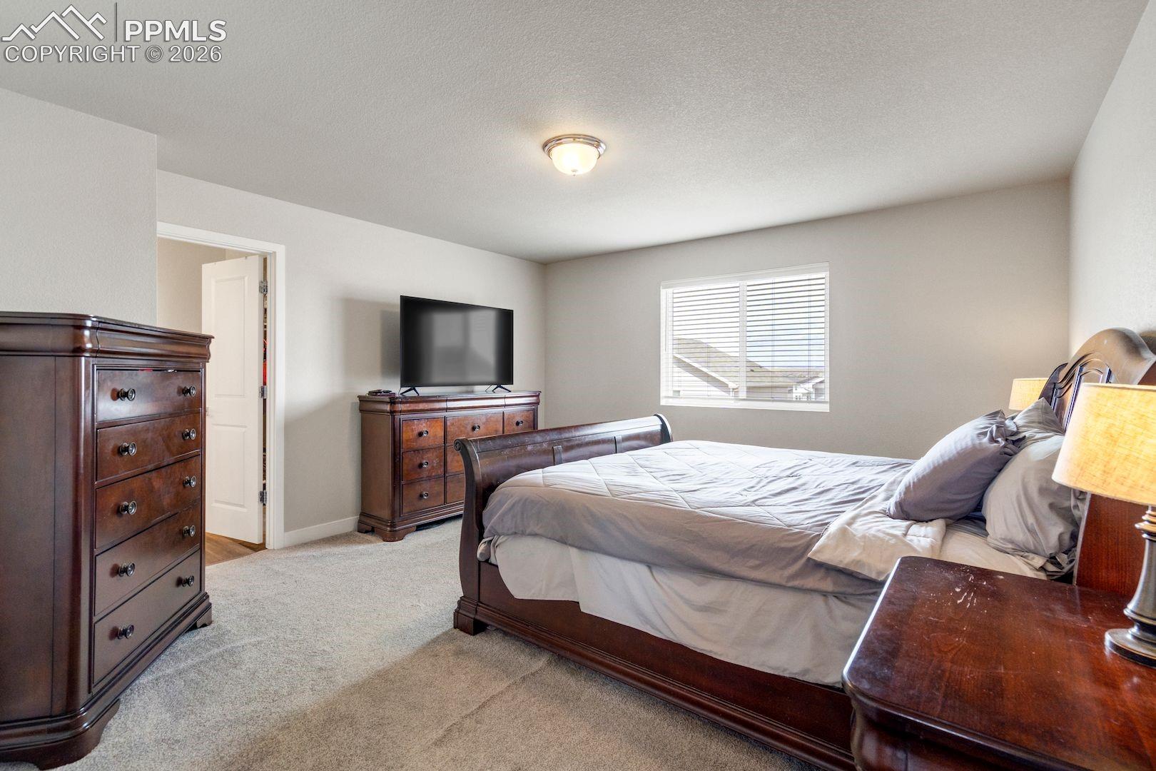 Bedroom featuring light carpet and a textured ceiling