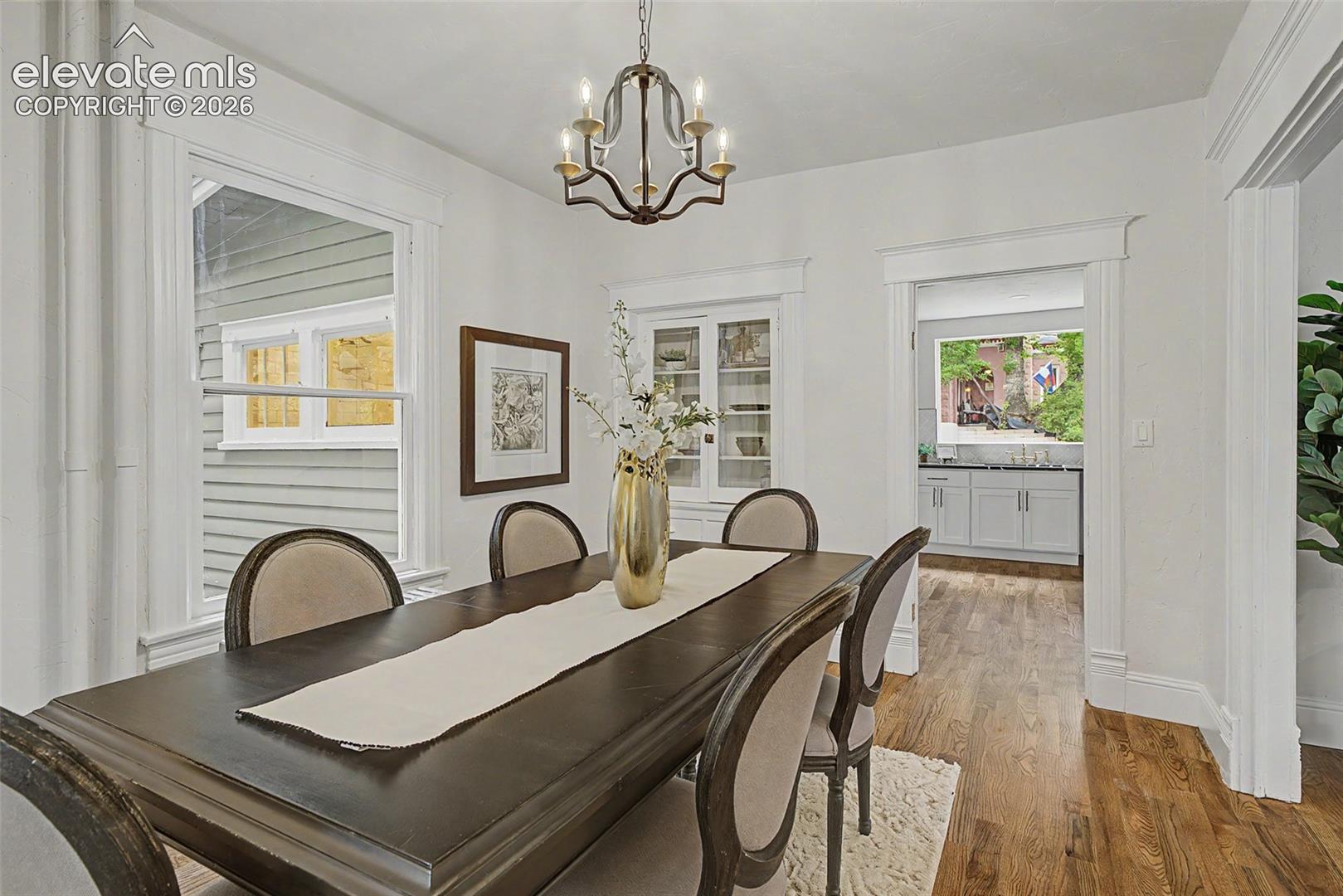 Dining area featuring wood-finish flooring, white trim, and a decorative chandelier