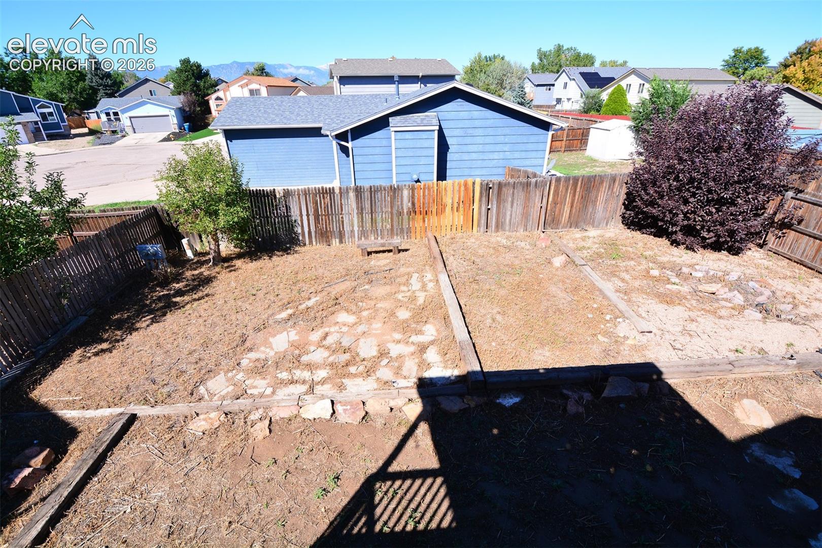 Fenced backyard with terraced landscaping and mature plantings
