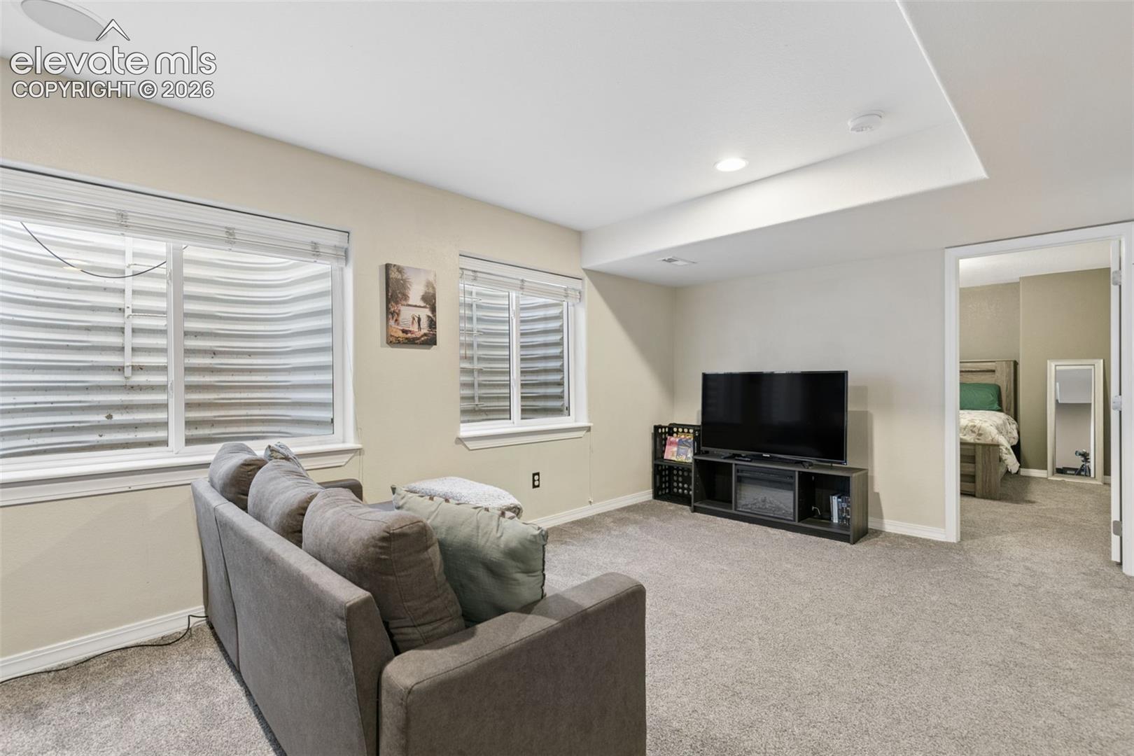 Recessed lighting, wall-to-wall carpeting, and a built-in media console with an electric fireplace