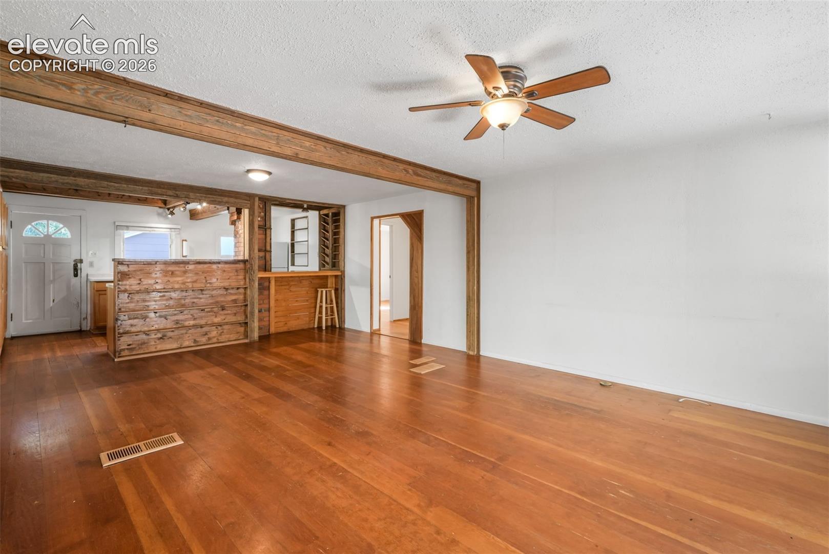 Wood-finish flooring throughout, exposed wood ceiling beams, and a built-in bar area with integrated shelving