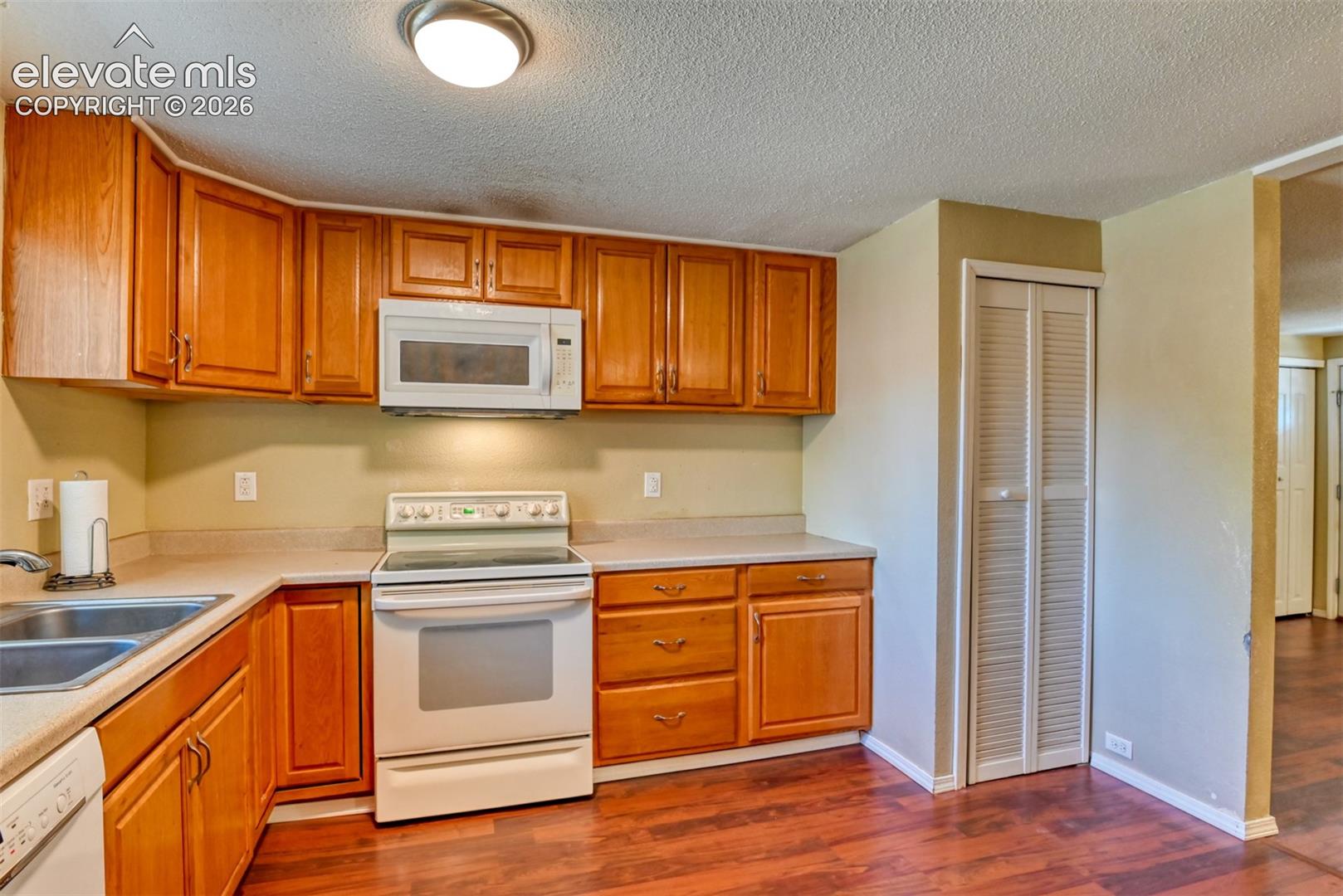 Kitchen featuring wood cabinetry, laminate countertops, a double basin sink, electric range, and a built-in microwave