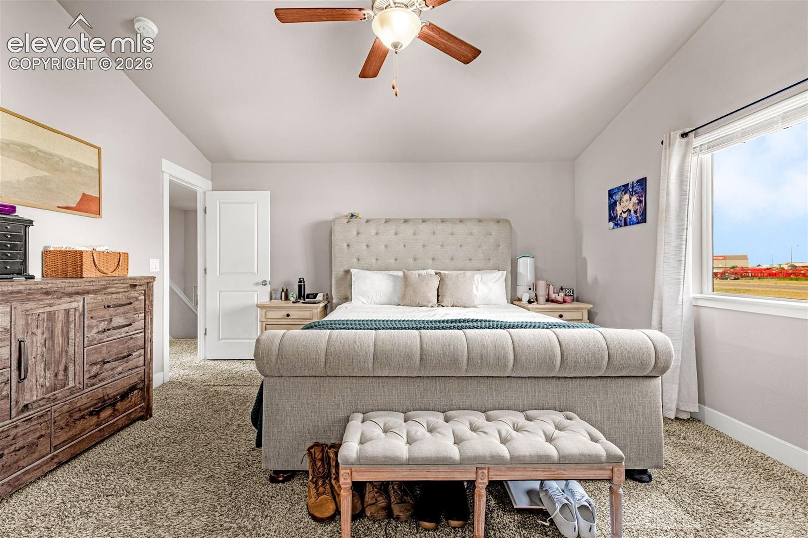 Carpeted room with a ceiling fan, white trim, and a window with a white frame