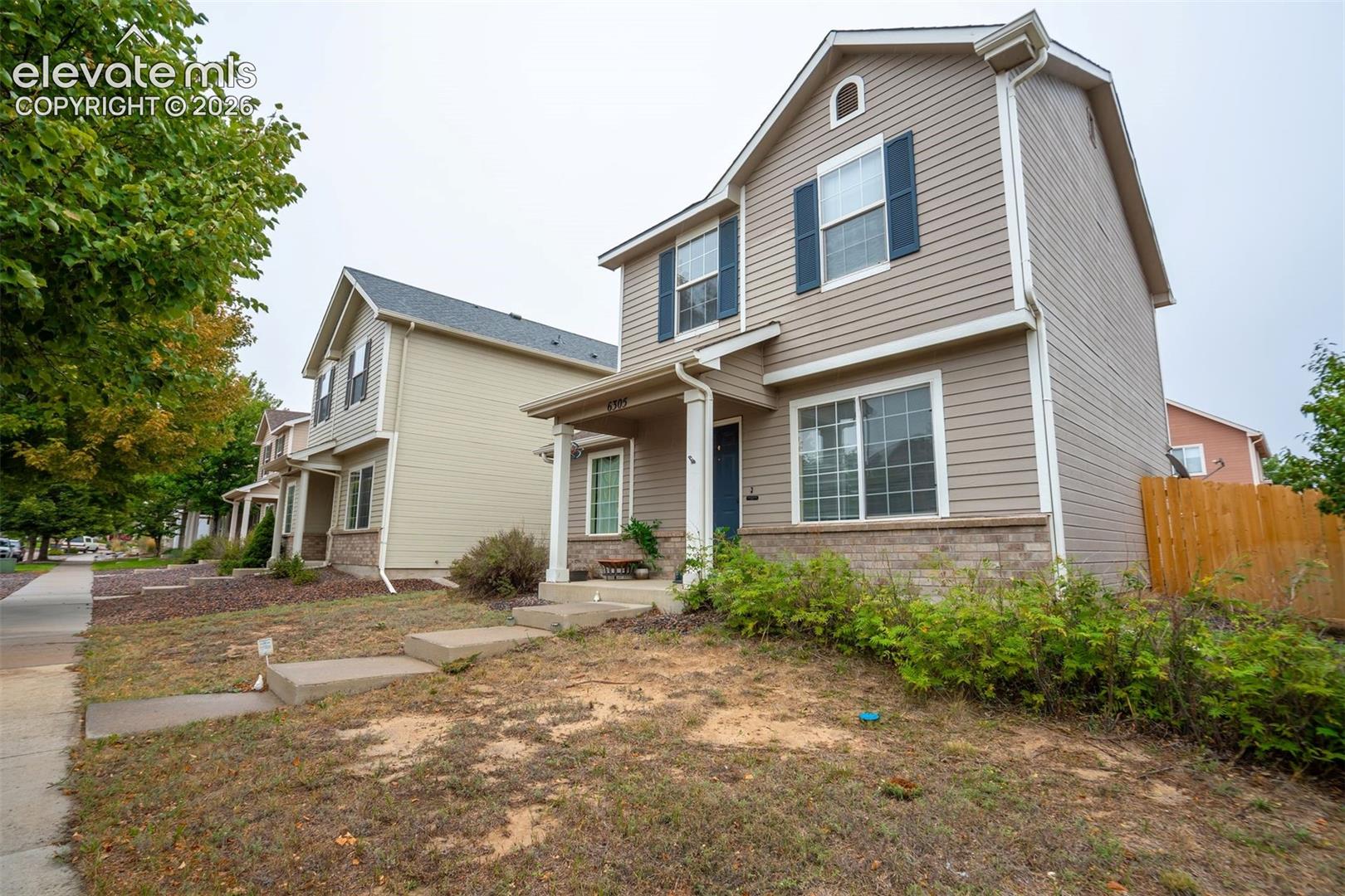 Two-story residence with horizontal siding, brick accent detailing, and dark shutters