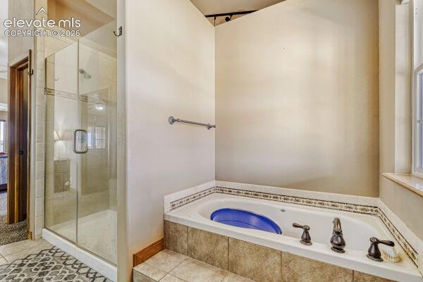 Bathroom featuring a built-in jetted tub with decorative tile surround, a separate glass-enclosed shower, and a window with a stone sill