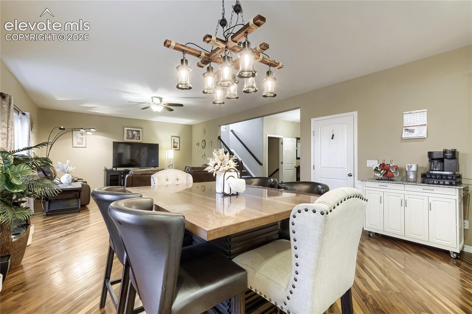 Warm wood flooring extends through this open-concept space, featuring a distinctive multi-bulb chandelier