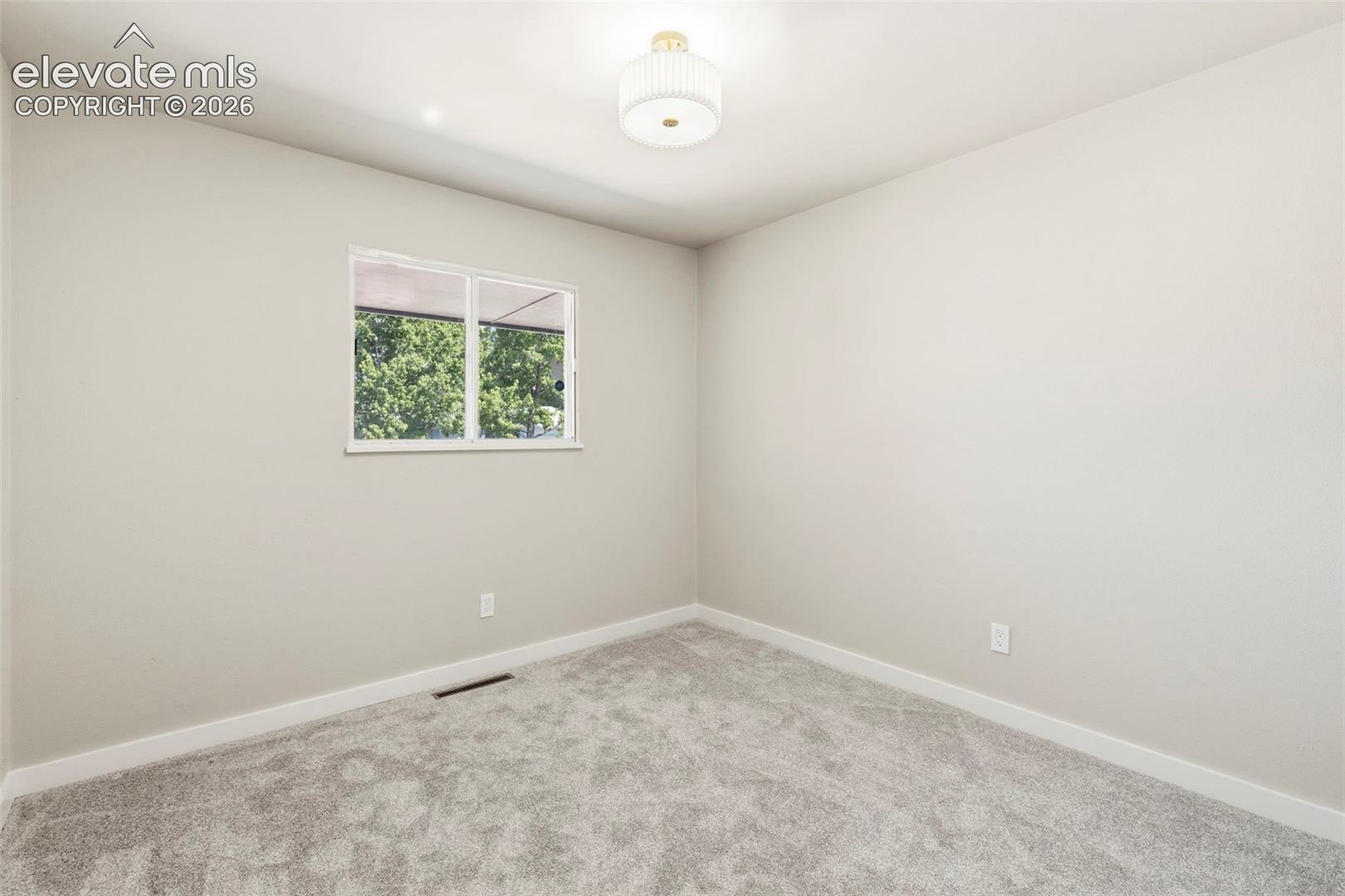Room featuring light gray wall paint, taupe carpeting, and white baseboards
