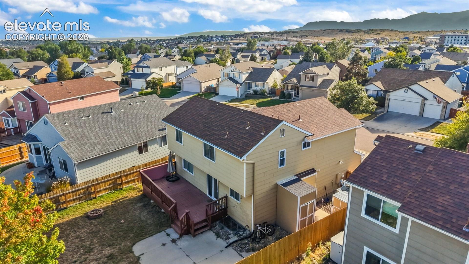 Rear exterior featuring a multi-level wood deck, concrete patio, and fenced backyard