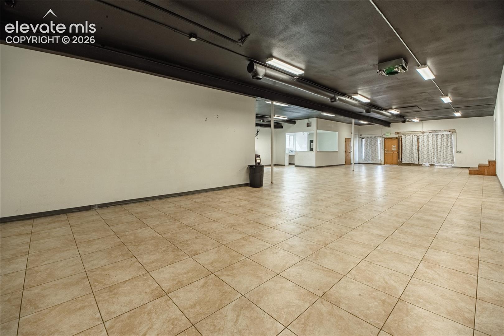 Expansive open-concept space featuring ceramic tile flooring, exposed ductwork, recessed lighting, and a partially enclosed office area