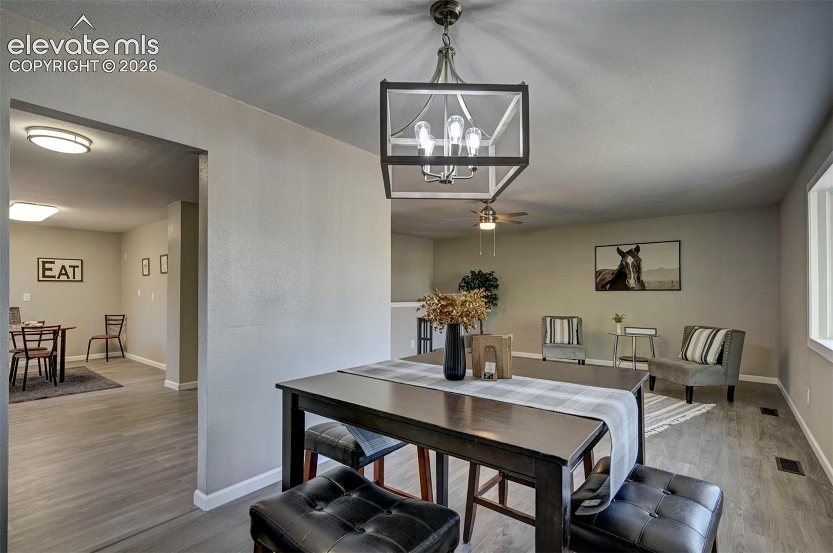 Open-concept living space featuring wood-finish flooring, a geometric metal-frame chandelier, recessed ceiling lighting, and a ceiling fan