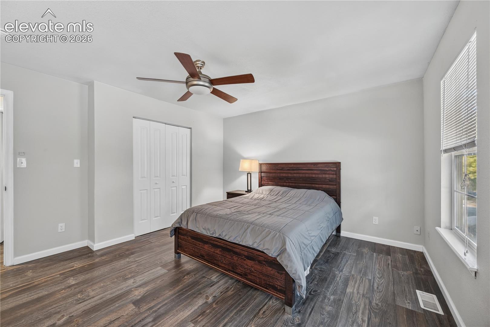 Neutral-toned walls, wood-finish flooring, ceiling fan, and double-door closet