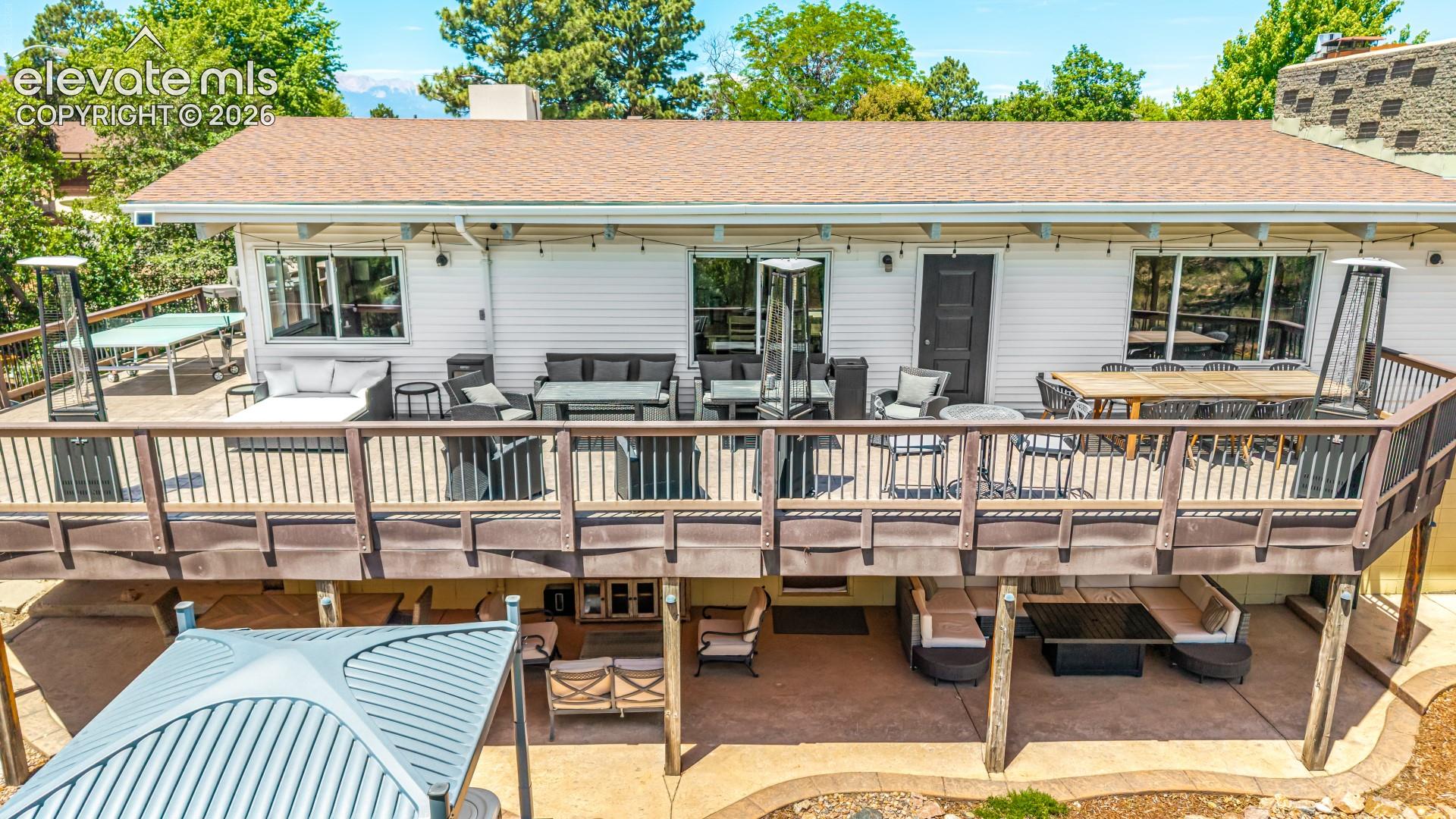 A final aerial pass shows the home's full footprint — deck, patio, hot tub, and storage shed — set against a backdrop of mature trees and rolling green space.