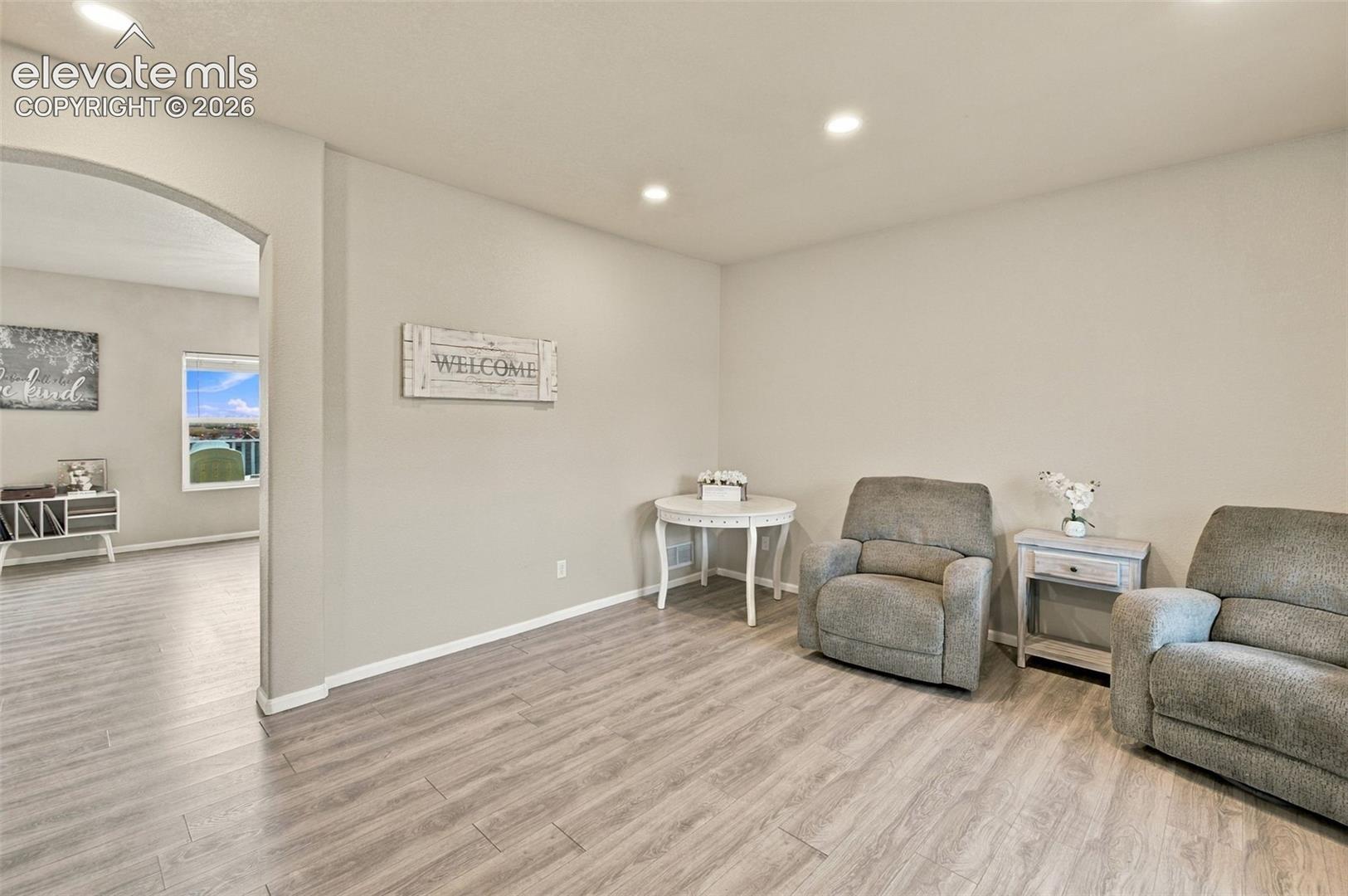 Neutral-toned room featuring wood-finish flooring, recessed lighting, and a prominent arched entryway