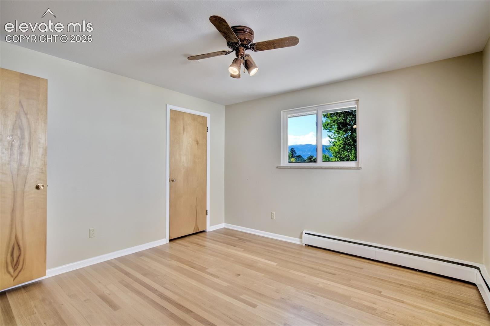 Interior space featuring wood-finish flooring, natural wood doors, ceiling fan with integrated lighting, and mountain scenery