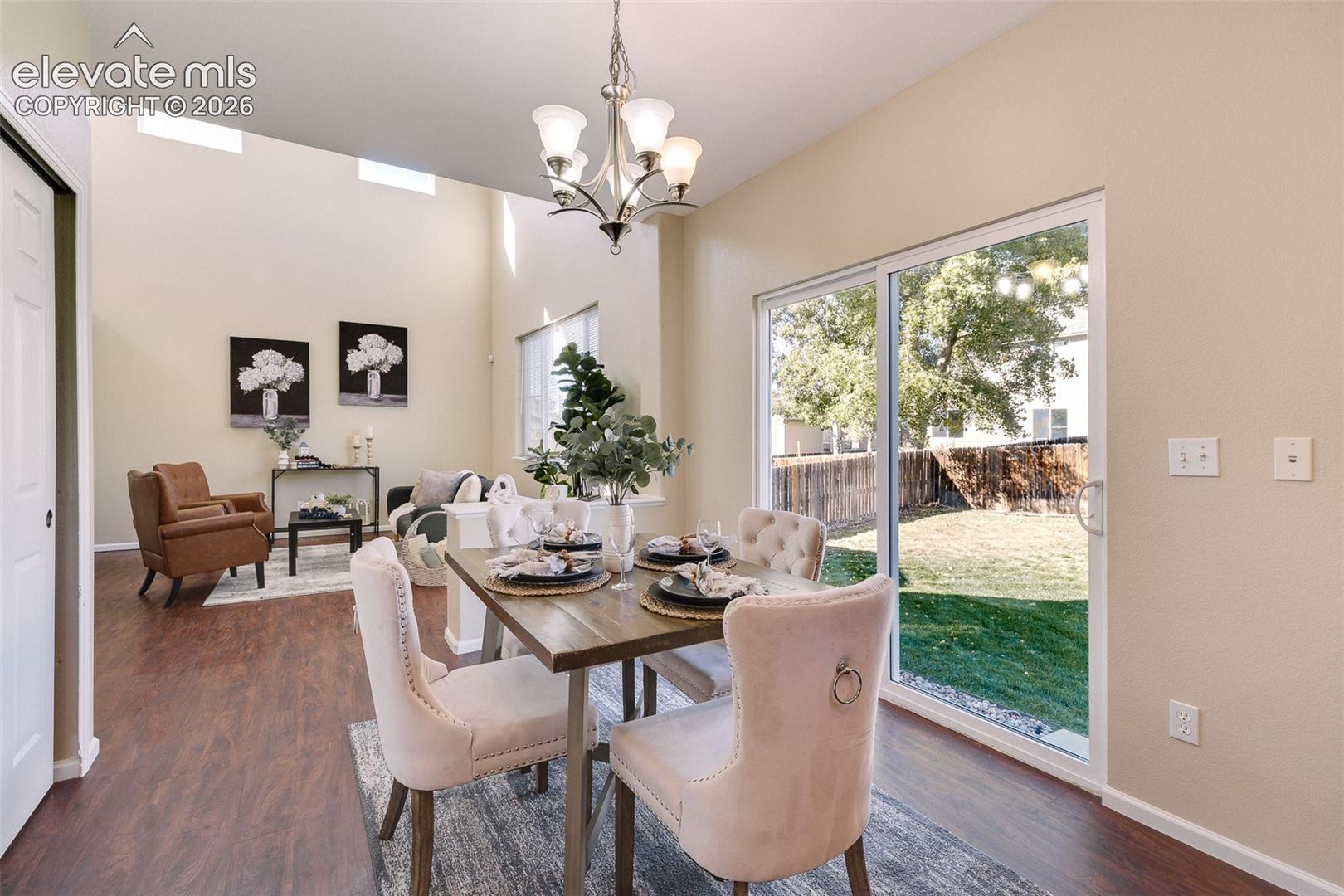 Vaulted ceilings, wood-finish flooring, sliding glass door, and multi-light chandelier