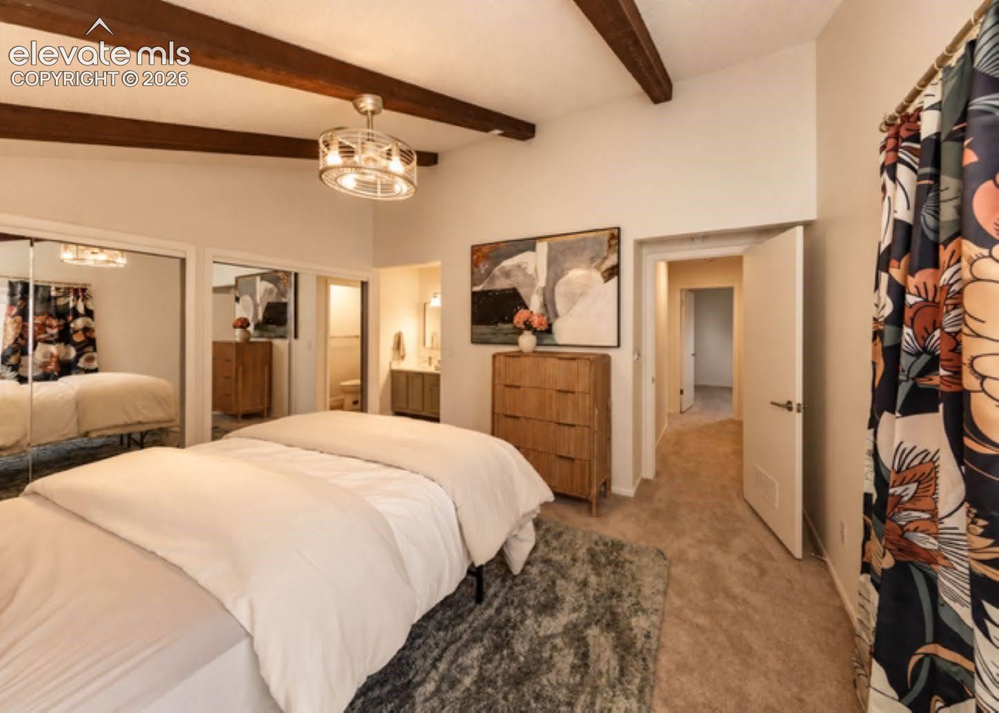 Vaulted ceiling with exposed wood-finish beams, mirrored closet doors, and a decorative industrial-style ceiling fan