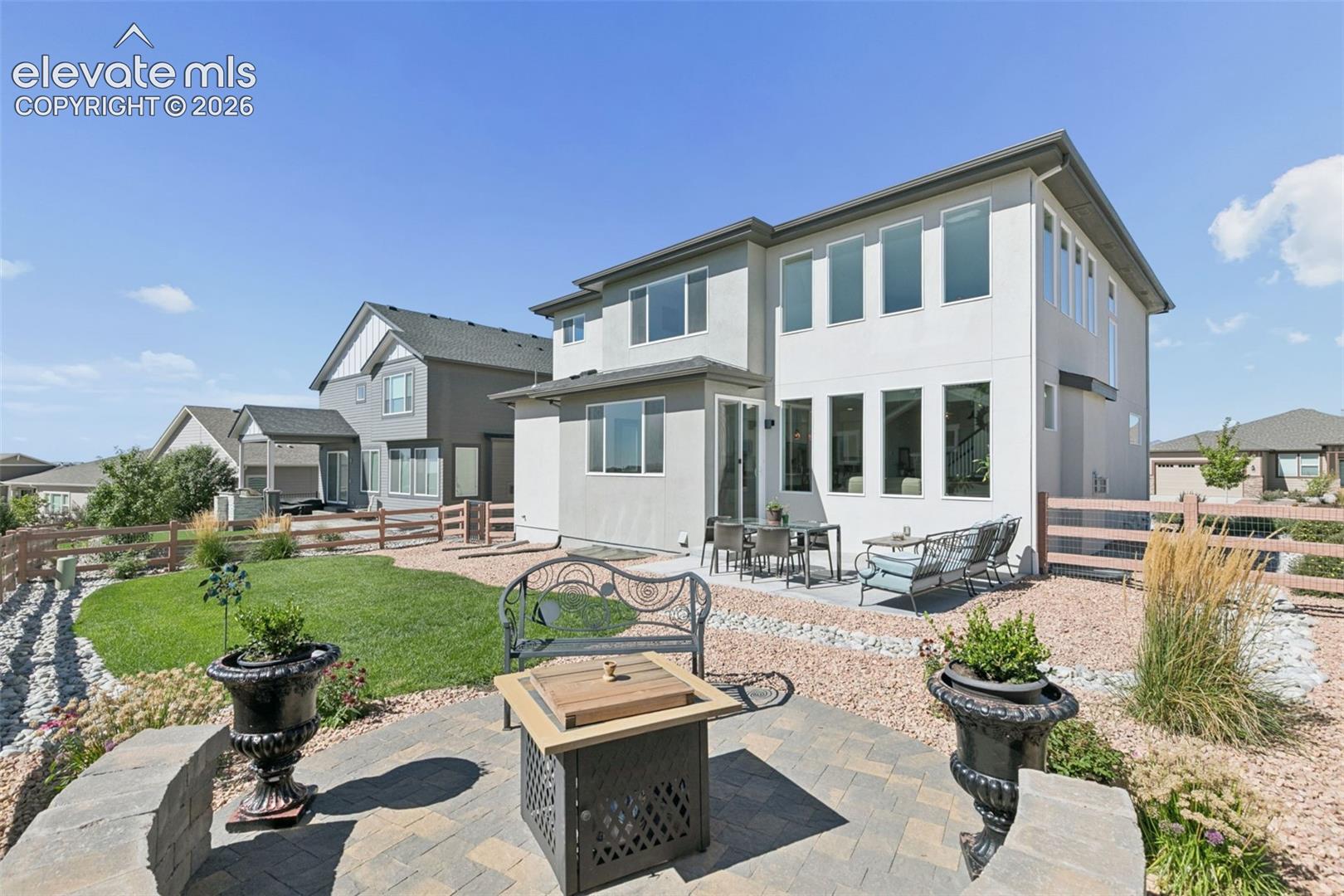 Expansive backyard featuring a stone patio, manicured lawn, and surrounding rock landscaping
