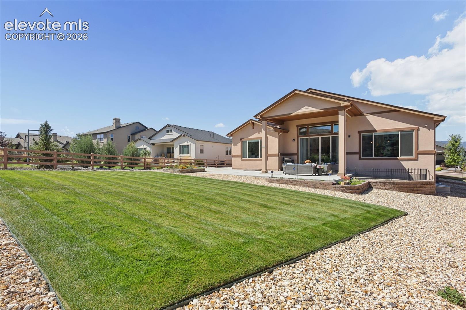 Expansive lawn area with gravel border, wood fence, and stucco exterior