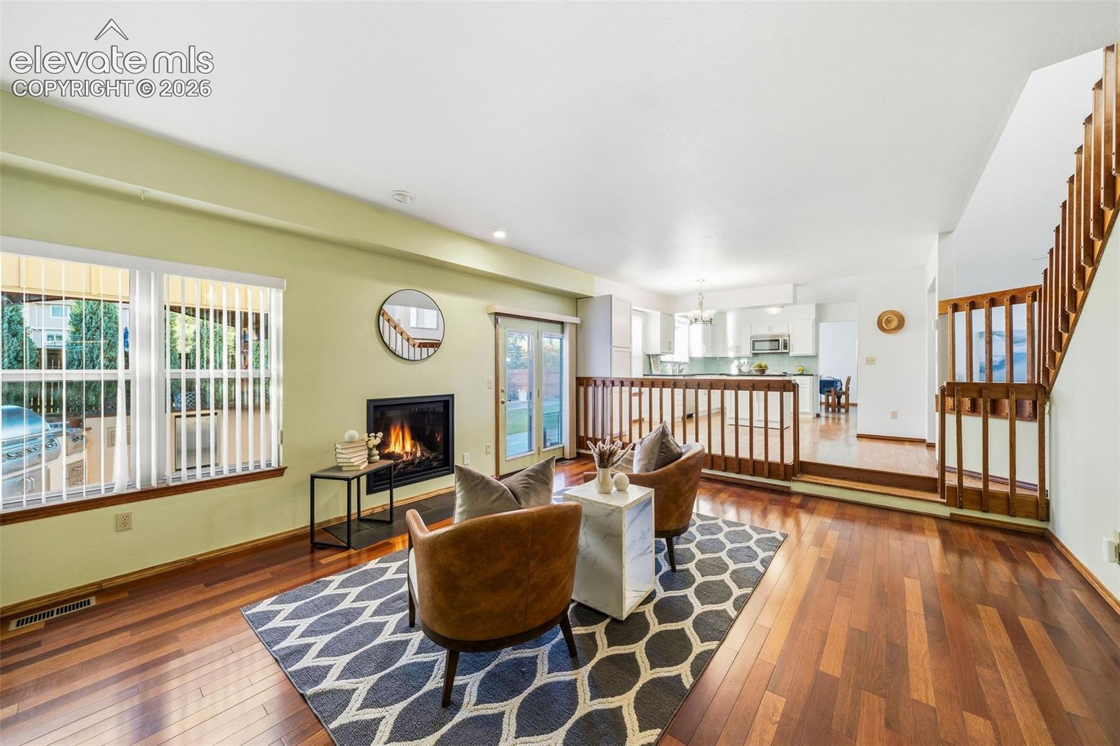 Living area featuring wood-finish flooring, a recessed fireplace, glass-paned French doors, and a wood balustrade staircase