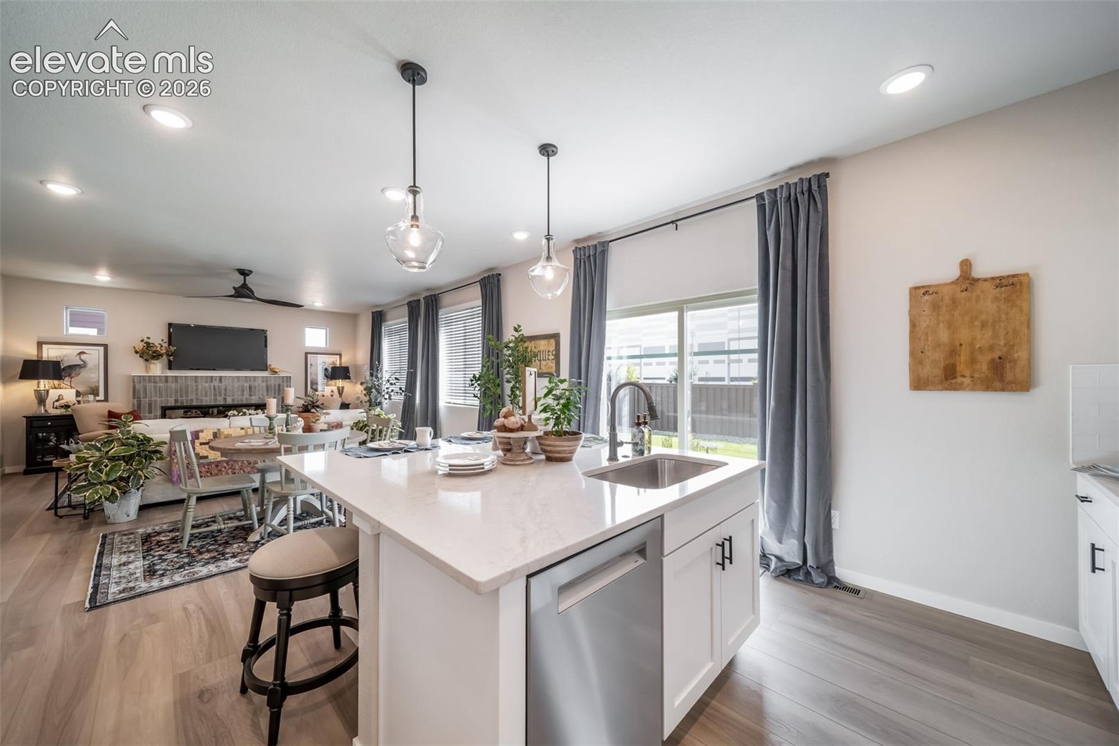 Kitchen island with a stainless steel sink, integrated dishwasher, and pendant lighting
*Photos of a model home*