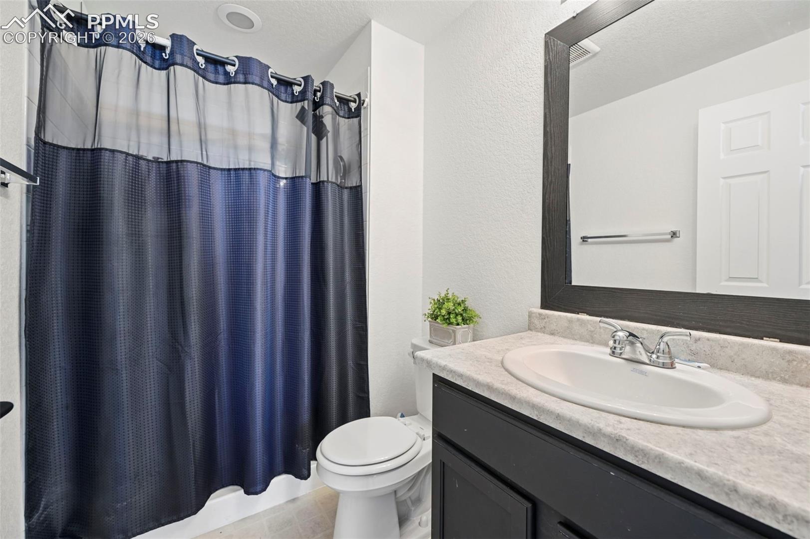 Bathroom featuring a single vanity with an integrated sink, a dark wood-framed mirror, and a toilet