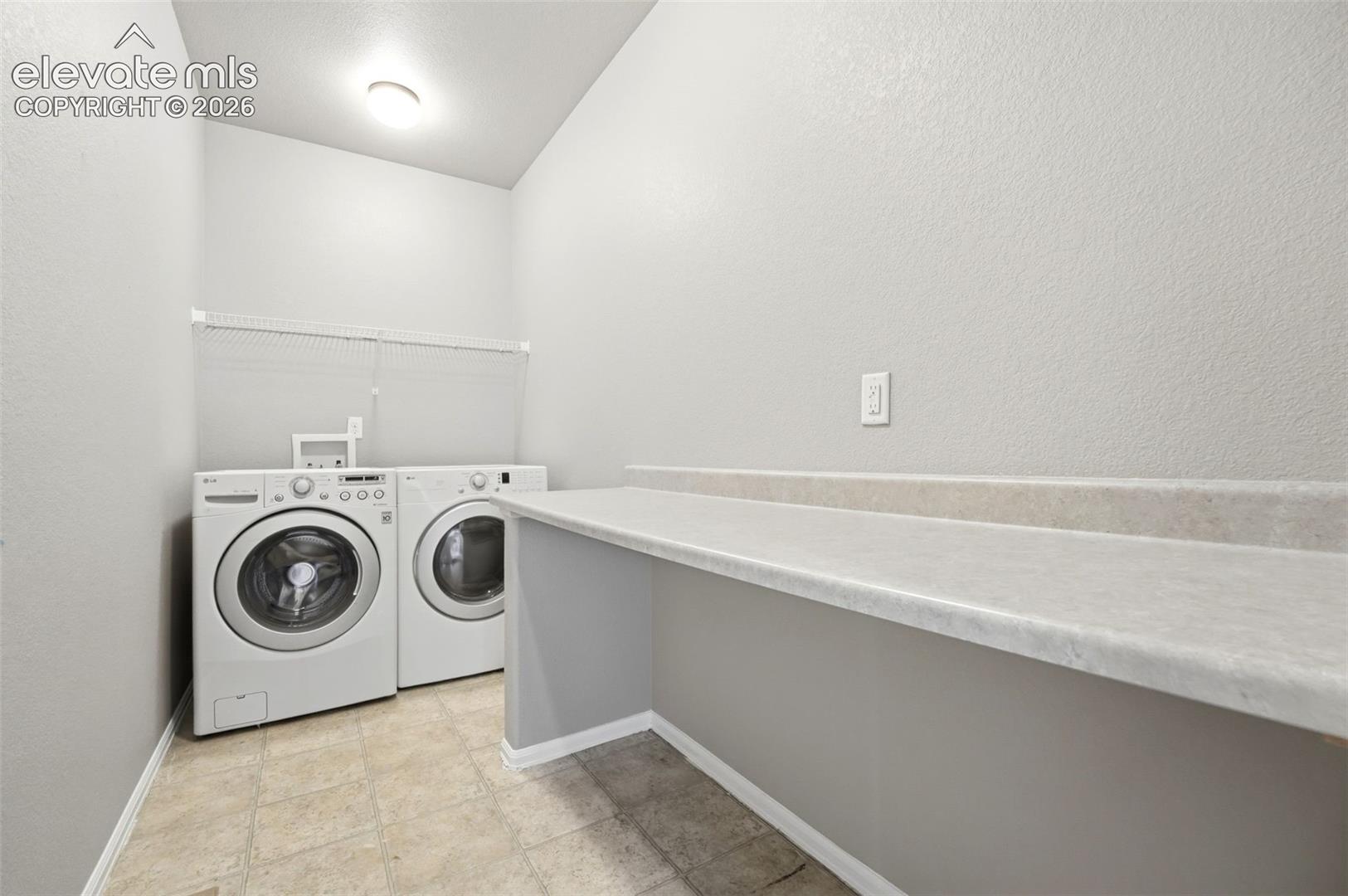 Dedicated laundry area featuring a built-in counter, wire shelving, and neutral-toned flooring