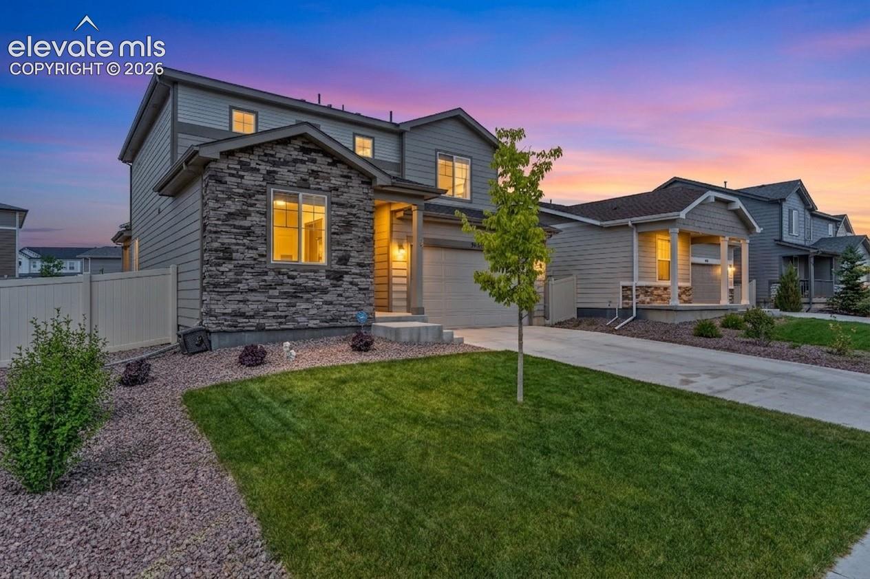 Two-story facade featuring stone and horizontal siding accents, an attached garage, and a concrete driveway