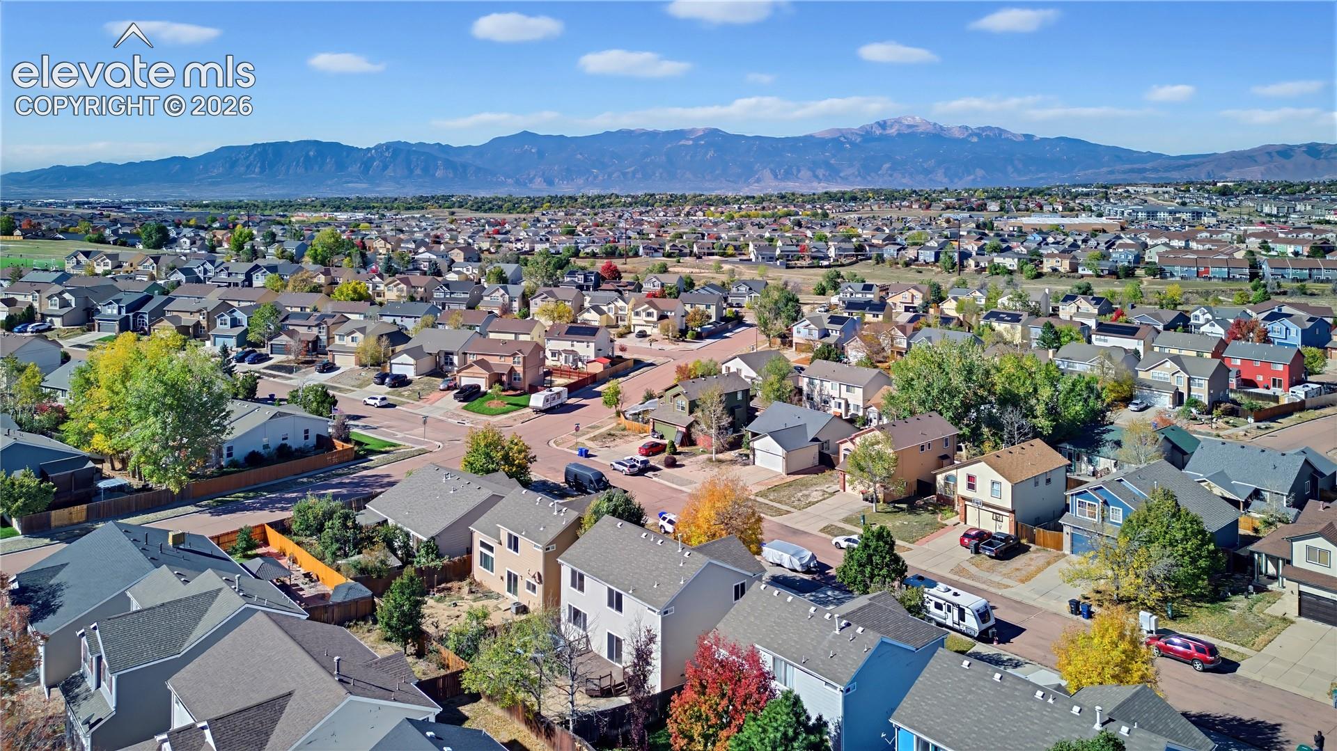 Aerial perspective of residential neighborhood featuring mature deciduous trees and prominent mountain backdrop