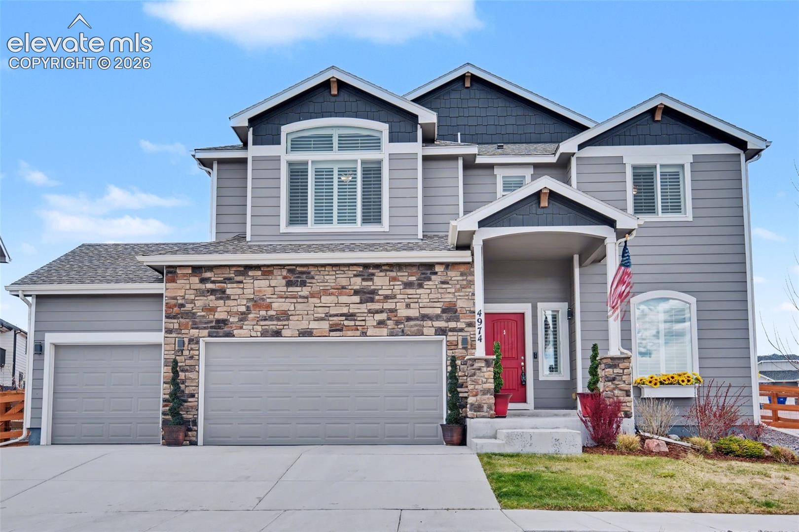 Contemporary exterior with stone accent, dual garage doors, and covered entryway