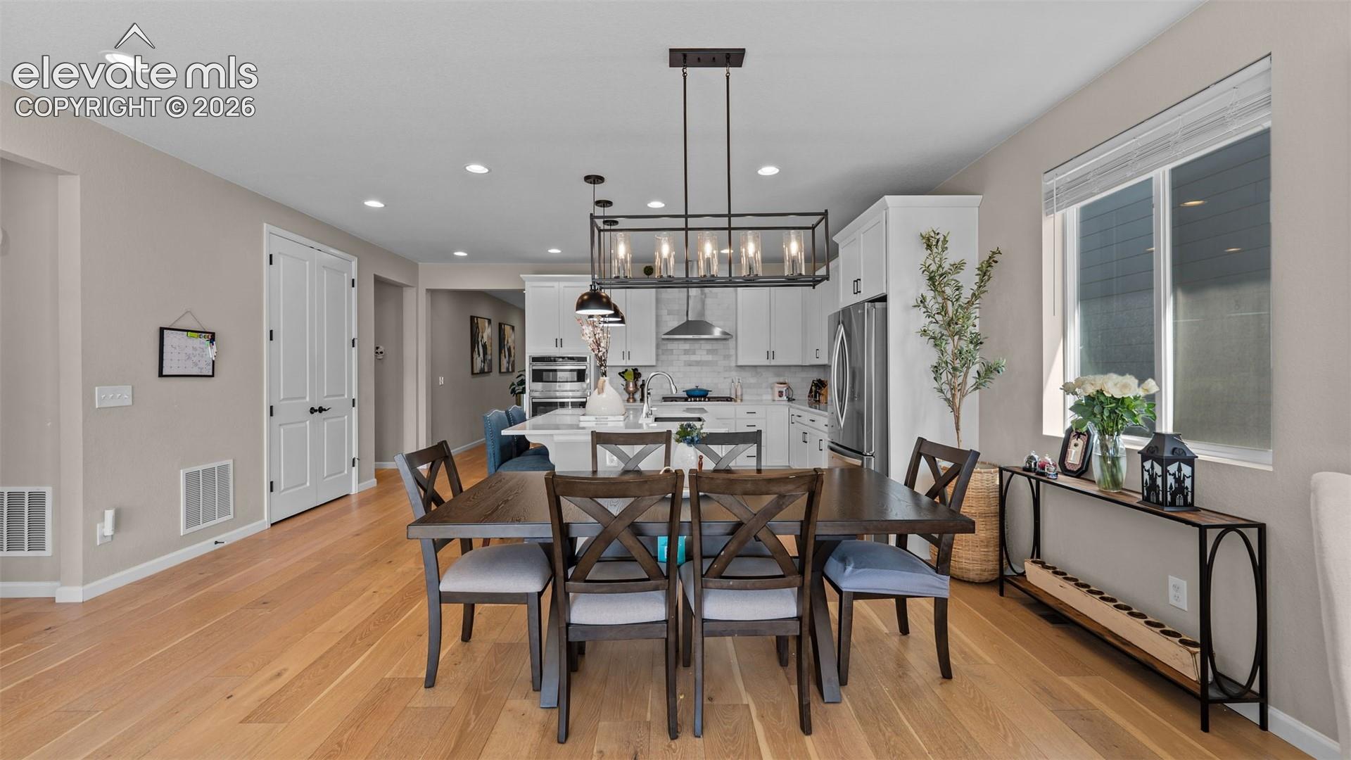 Open-concept design with wood-finish flooring, recessed lighting, and a modern rectangular chandelier