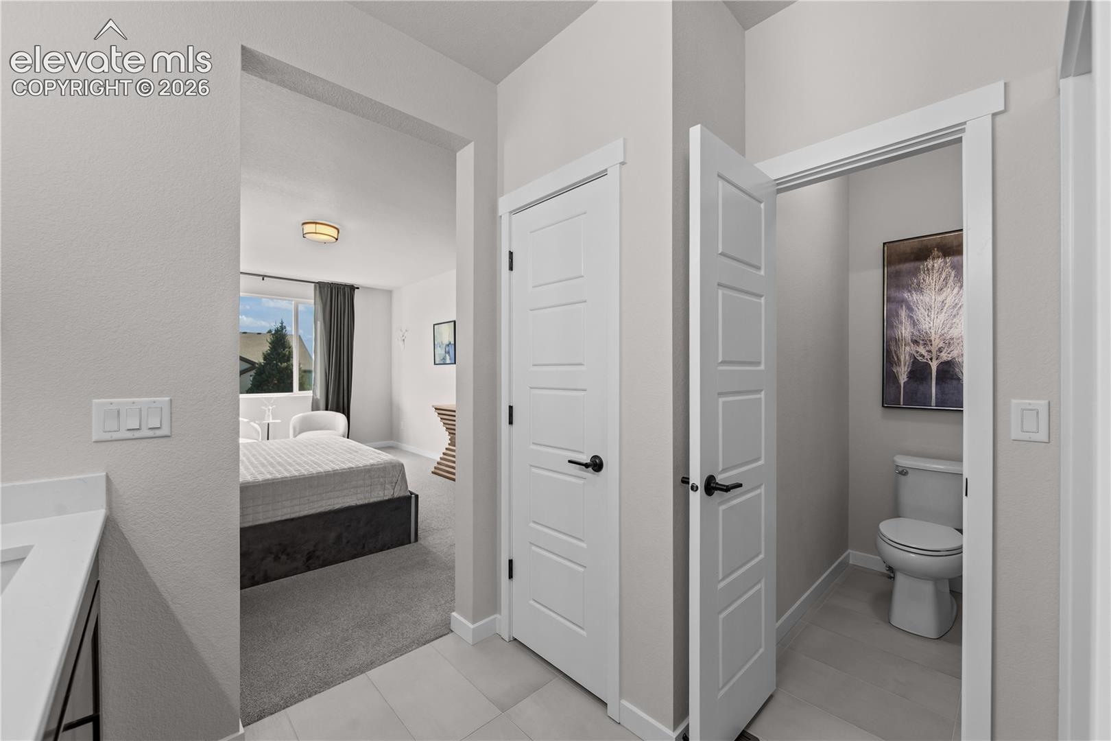 Neutral-toned interior featuring crisp white multi-panel doors with matte black hardware, large-format tile flooring, and clean, minimalist trim