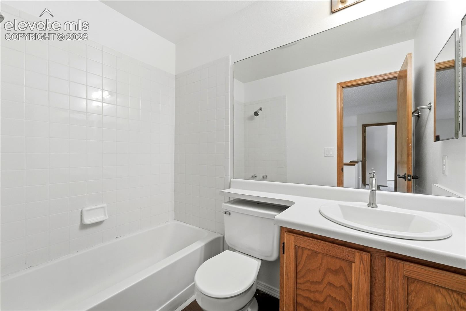 White subway tile surround, built-in bathtub, and full-width mirror