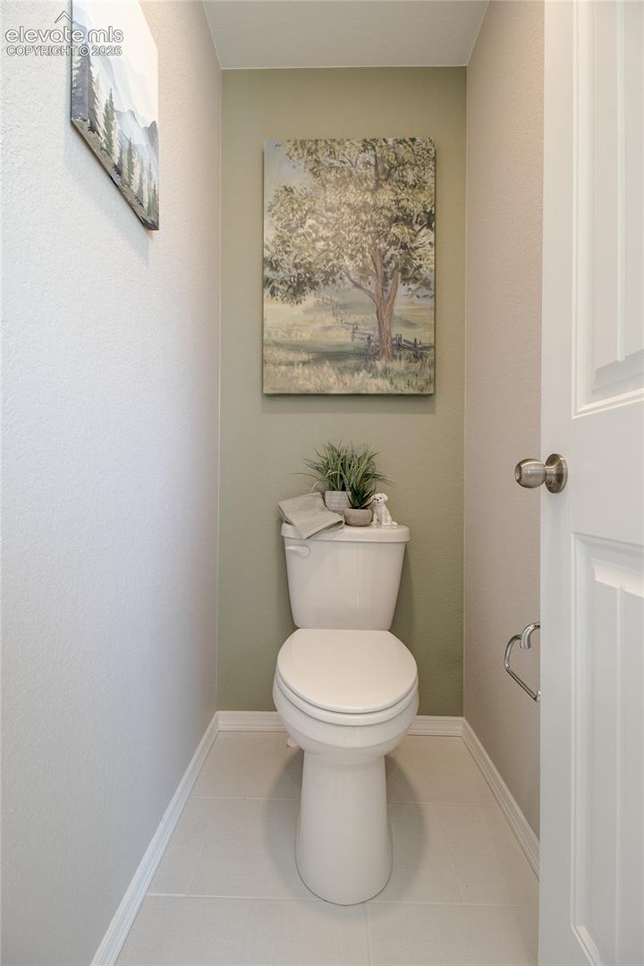 Powder room featuring a two-piece toilet, matte-finish tile flooring, and a six-panel interior door with a brushed-metal knob