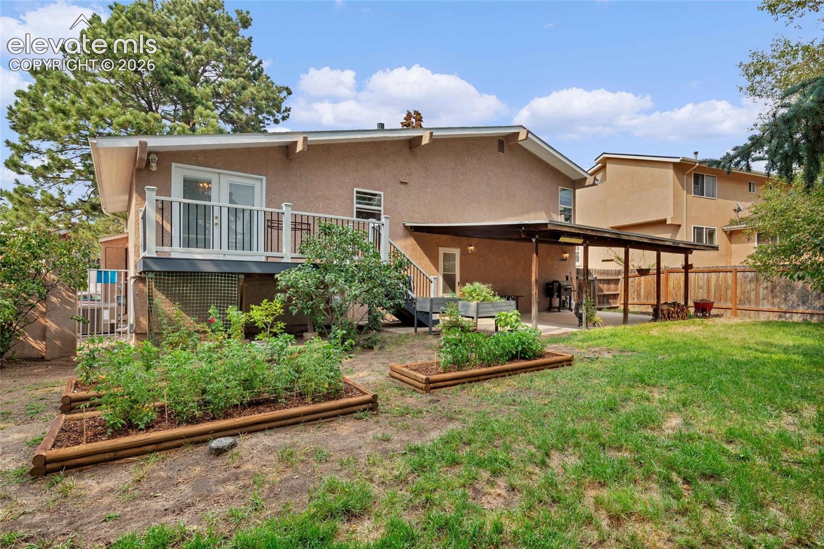 Expansive backyard with a manicured lawn, tiered garden beds, and mature trees