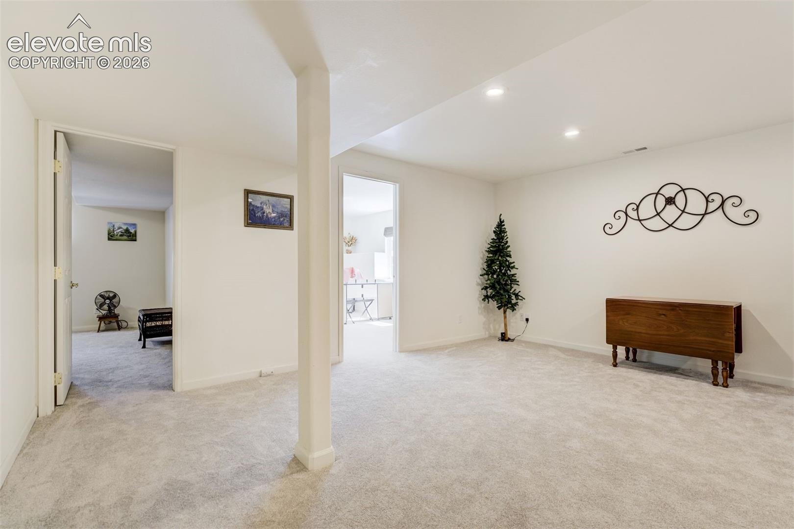 Neutral interior space featuring carpeted flooring, recessed lighting, and a support column