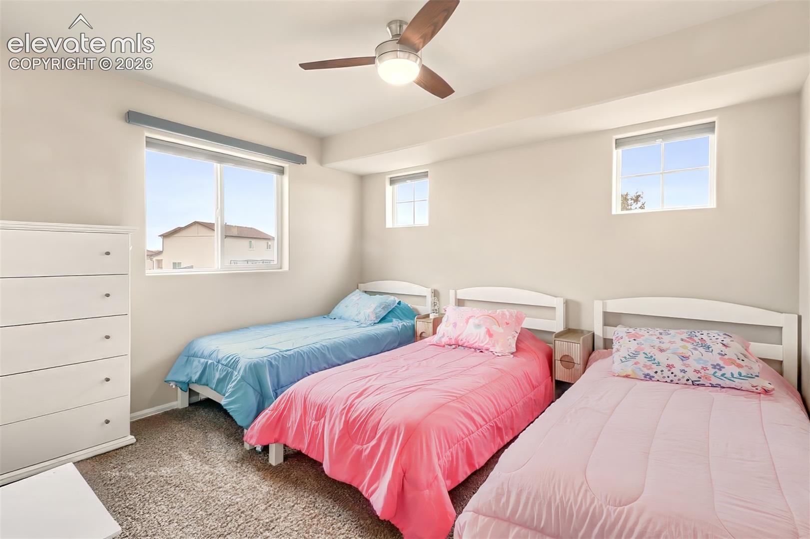 Neutral interior walls, wall-to-wall carpeting, ceiling fan with integrated lighting, and multiple windows with grid detailing